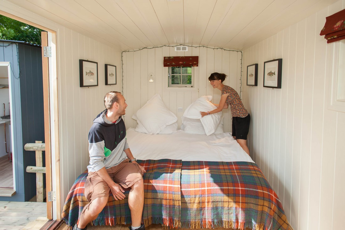 Couple making the bed at Meon Springs Shepherd's Huts